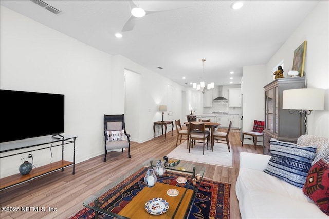 living room with light wood-style floors, a ceiling fan, recessed lighting, a chandelier, and baseboards