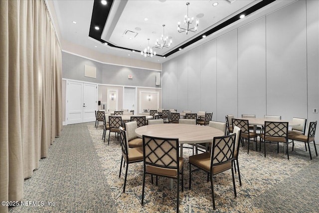 dining space with a high ceiling, a decorative wall, a chandelier, and carpet flooring