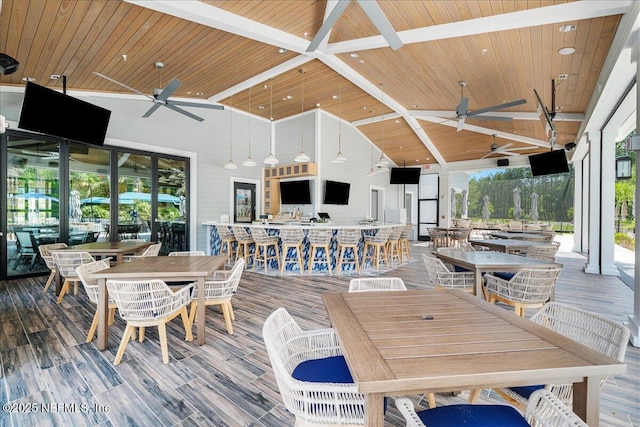 wooden deck with ceiling fan, outdoor dining space, and a bar