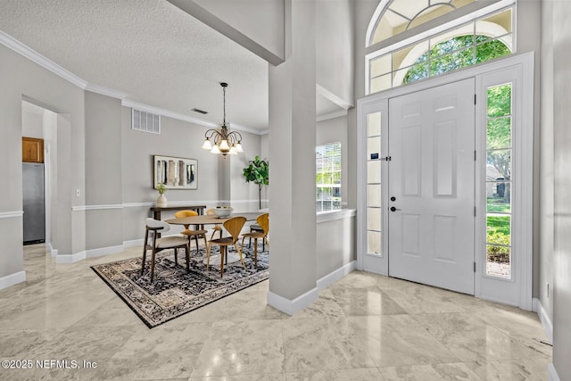 13759 Wingfield Pl, Jacksonville, FL 32224 - entrance foyer featuring crown molding, a chandelier, baseboards, light marble finish flooring, and a textured ceiling