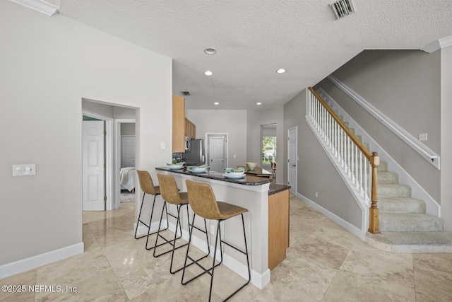 13759 Wingfield Pl, Jacksonville, FL 32224 - kitchen featuring freestanding refrigerator, a textured ceiling, a kitchen breakfast bar, dark countertops, and baseboards