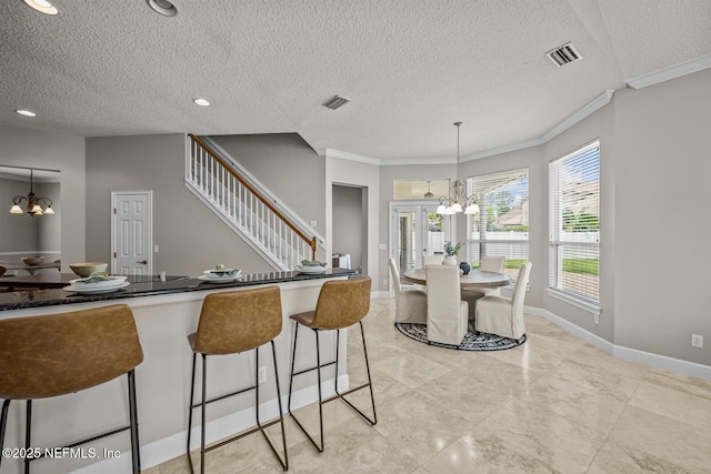 13759 Wingfield Pl, Jacksonville, FL 32224 - kitchen featuring a chandelier, crown molding, a textured ceiling, a breakfast bar, and hanging light fixtures