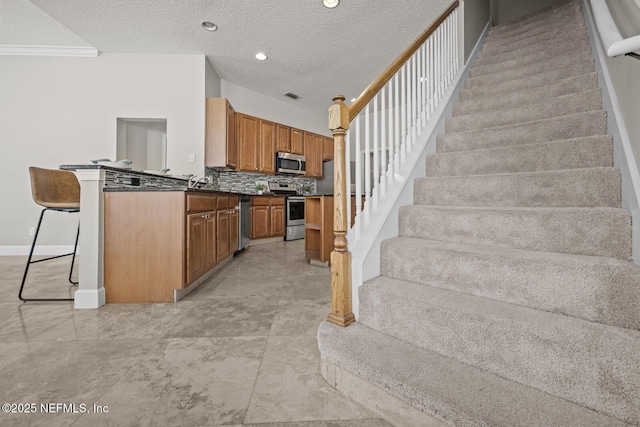 13759 Wingfield Pl, Jacksonville, FL 32224 - kitchen with appliances with stainless steel finishes, brown cabinets, backsplash, dark countertops, and a textured ceiling