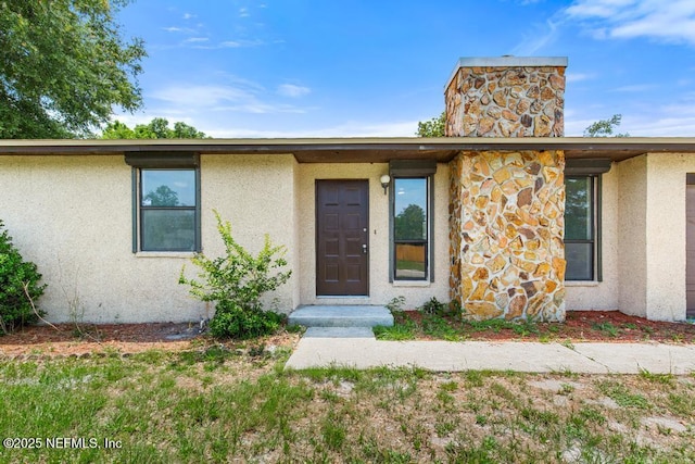 1169 Tumbleweed Dr, Orange Park, FL 32065 - doorway to property featuring a chimney, stucco siding, and stone siding