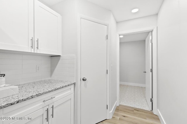 1169 Tumbleweed Dr, Orange Park, FL 32065 - kitchen featuring white cabinetry, tasteful backsplash, light stone counters, light wood finished floors, and baseboards