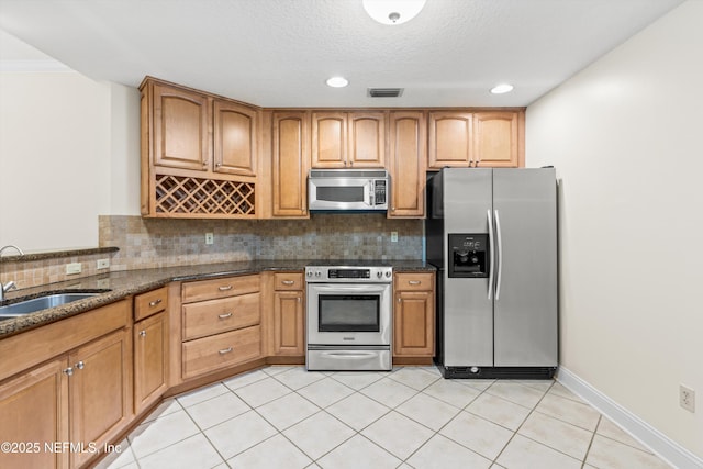 100 Bermuda Bay Cir Unit 104, Ponte Vedra Beach, FL 32082 - kitchen with stainless steel appliances, a sink, backsplash, dark stone countertops, and a textured ceiling