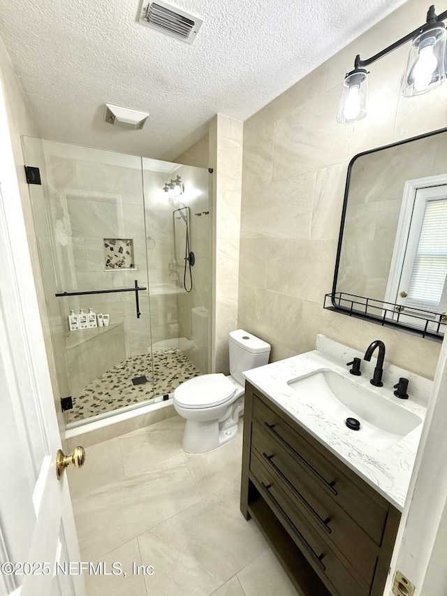 12753 Burning Tree Ln W, Jacksonville, FL 32223 - full bathroom with tile walls, vanity, a textured ceiling, a stall shower, and toilet