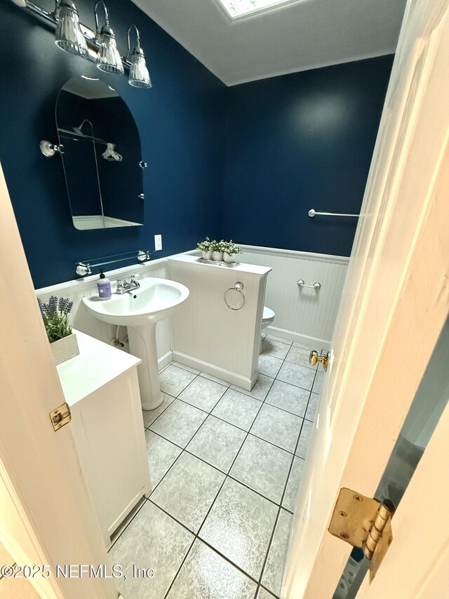 12753 Burning Tree Ln W, Jacksonville, FL 32223 - half bathroom with toilet, wainscoting, tile patterned floors, and a sink