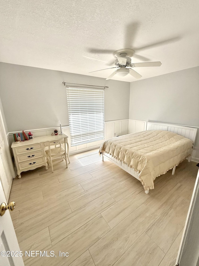 12753 Burning Tree Ln W, Jacksonville, FL 32223 - bedroom with light wood-type flooring, a textured ceiling, wainscoting, and ceiling fan