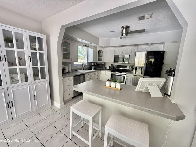 12753 Burning Tree Ln W, Jacksonville, FL 32223 - kitchen with appliances with stainless steel finishes, a sink, a textured ceiling, glass insert cabinets, and light tile patterned floors