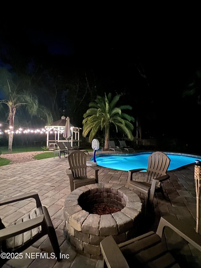 12753 Burning Tree Ln W, Jacksonville, FL 32223 - pool at night with an outdoor fire pit, a patio area, and an outdoor pool