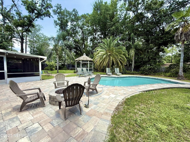 12753 Burning Tree Ln W, Jacksonville, FL 32223 - outdoor pool featuring a patio area, a sunroom, an outdoor fire pit, a lawn, and view of wooded area