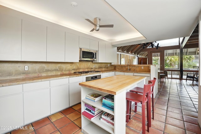 1927 Beachside Ct, Atlantic Beach, FL 32233 - kitchen with stainless steel appliances, a kitchen breakfast bar, butcher block counters, a ceiling fan, and decorative backsplash