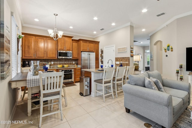 2695 Morning Light Ct, Flagler Beach, FL 32136 - kitchen with stainless steel appliances, open floor plan, a peninsula, brown cabinetry, and backsplash