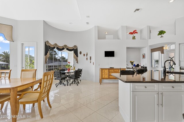 12 Collingville Ct, Palm Coast, FL 32137 - kitchen with a sink, dark countertops, light tile patterned flooring, a towering ceiling, and white cabinets