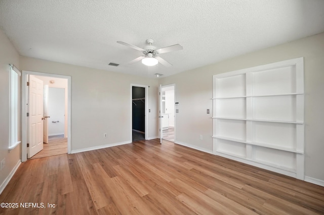 1205 Eagle Bend Ct, Jacksonville, FL 32226 - unfurnished bedroom featuring a textured ceiling, light wood-style floors, baseboards, a spacious closet, and a ceiling fan