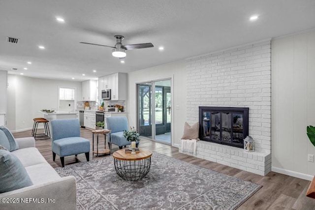 10859 Windy Gale Dr W, Jacksonville, FL 32218 - living area with light wood-type flooring, a ceiling fan, recessed lighting, a brick fireplace, and baseboards