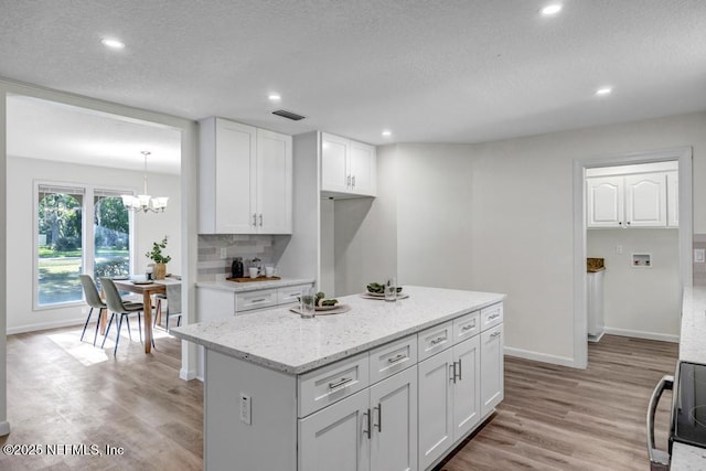 10859 Windy Gale Dr W, Jacksonville, FL 32218 - kitchen featuring white cabinetry, light wood finished floors, a chandelier, baseboards, and recessed lighting