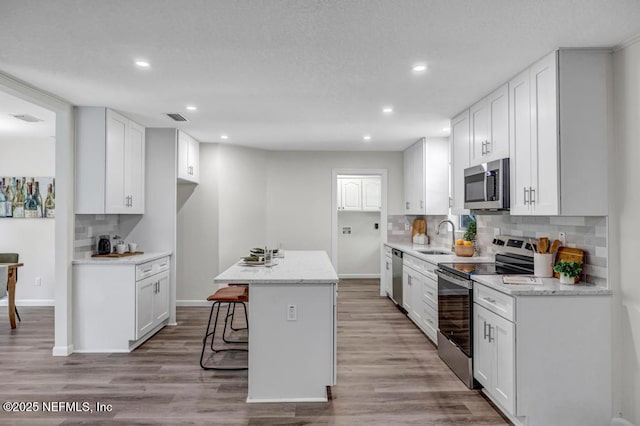 10859 Windy Gale Dr W, Jacksonville, FL 32218 - kitchen featuring stainless steel appliances, backsplash, recessed lighting, white cabinetry, and a sink