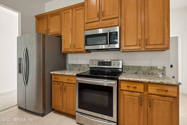 3384 Olympic Dr, Green Cove Springs, FL 32043 - kitchen with stainless steel appliances, light tile patterned floors, light stone countertops, and brown cabinets