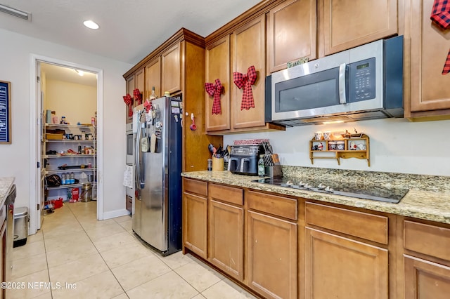 1071 Wetland Ridge Cir, Middleburg, FL 32068 - kitchen with appliances with stainless steel finishes, brown cabinetry, light tile patterned flooring, light stone countertops, and recessed lighting