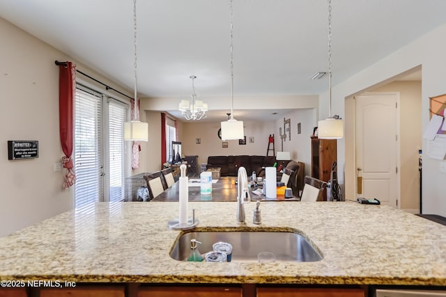 1071 Wetland Ridge Cir, Middleburg, FL 32068 - kitchen with a sink, open floor plan, a chandelier, light stone counters, and hanging light fixtures