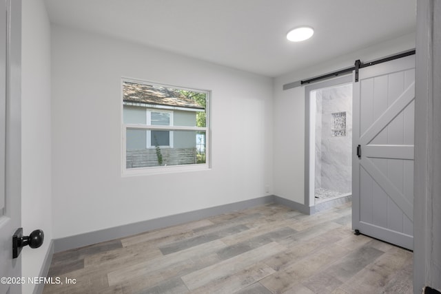 2210 Lamee Ave, Jacksonville, FL 32207 - unfurnished bedroom featuring light wood-style flooring, a barn door, and baseboards