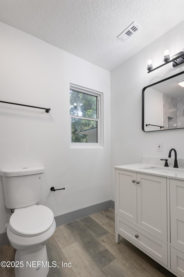 2210 Lamee Ave, Jacksonville, FL 32207 - bathroom with wood finished floors, a textured ceiling, toilet, vanity, and baseboards