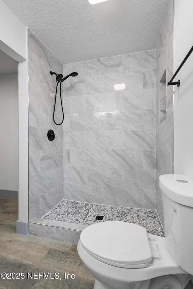 2210 Lamee Ave, Jacksonville, FL 32207 - bathroom featuring toilet, tiled shower, and a textured ceiling