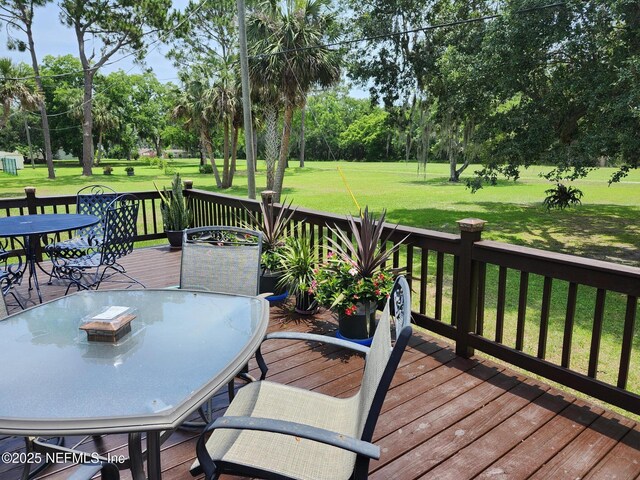 109 Laurel Ln, Crescent City, FL 32112 - wooden terrace with outdoor dining space, a lawn, and view of scattered trees