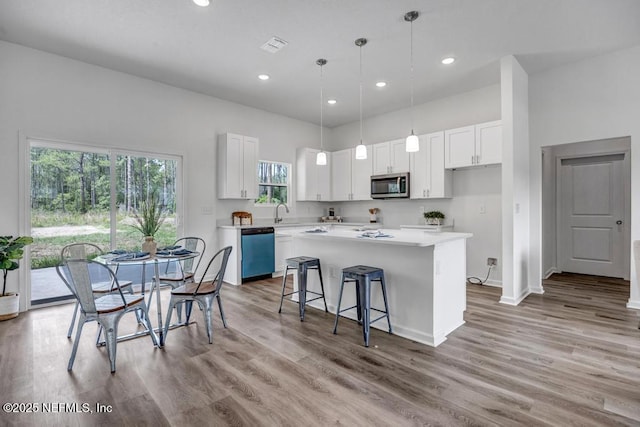 4410 Vicki St, Hastings, FL 32145 - kitchen featuring dishwashing machine, stainless steel microwave, a center island, white cabinets, and light wood-style floors