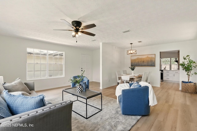 4923 Lofty Pines Cir E, Jacksonville, FL 32210 - living room featuring light wood finished floors, a chandelier, ceiling fan, baseboards, and a textured ceiling