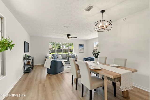 4923 Lofty Pines Cir E, Jacksonville, FL 32210 - dining room with light wood-style flooring, a ceiling fan, a chandelier, baseboards, and a textured ceiling