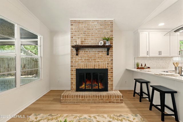 4923 Lofty Pines Cir E, Jacksonville, FL 32210 - living room featuring light wood-style floors, ornamental molding, baseboards, a brick fireplace, and recessed lighting