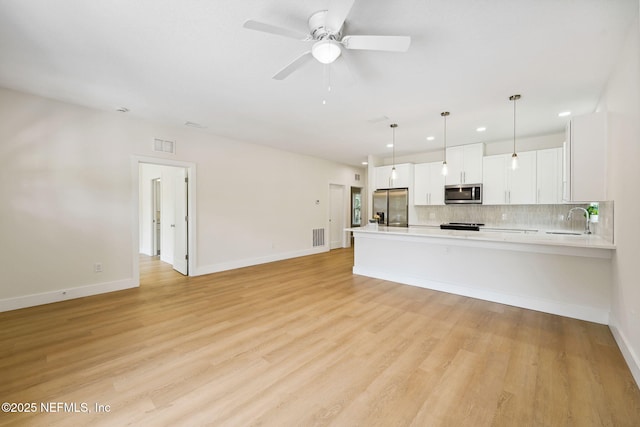 unfurnished living room with recessed lighting, a sink, ceiling fan, light wood-type flooring, and baseboards