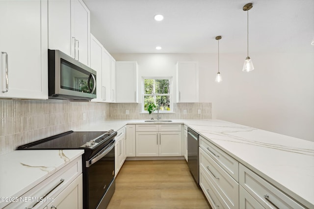 kitchen featuring stainless steel appliances, a sink, white cabinetry, decorative backsplash, and recessed lighting