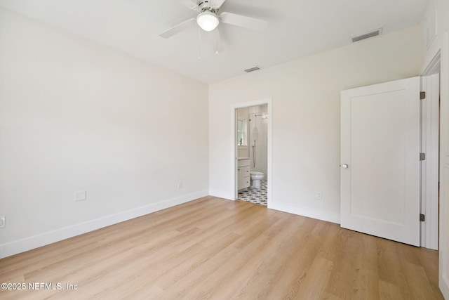 unfurnished bedroom with baseboards, wood finished floors, ensuite bathroom, and a ceiling fan