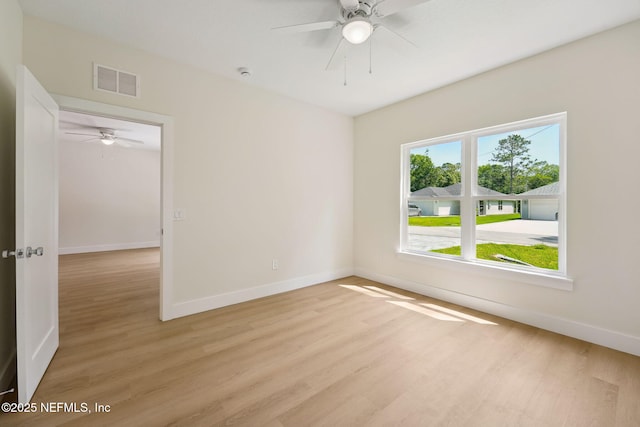 empty room with light wood-type flooring, a ceiling fan, and baseboards
