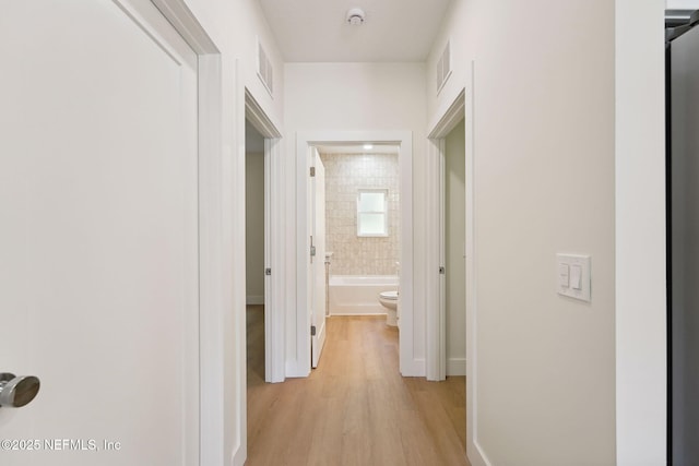 corridor with light wood-style flooring and baseboards
