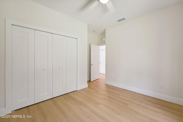unfurnished bedroom featuring light wood-style flooring, baseboards, and a closet