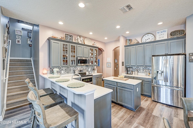3051 Paddle Creek Dr, Green Cove Springs, FL 32043 - kitchen with appliances with stainless steel finishes, arched walkways, gray cabinets, light countertops, and recessed lighting