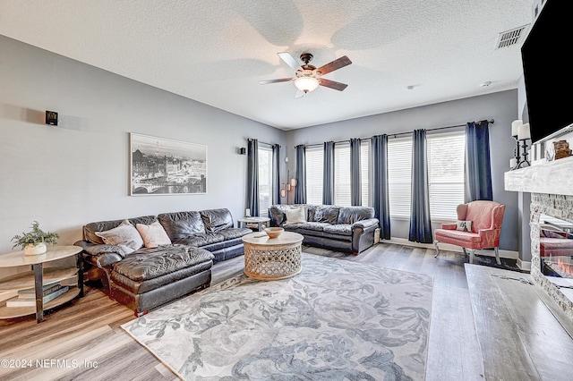 3051 Paddle Creek Dr, Green Cove Springs, FL 32043 - living area with a ceiling fan, light wood-style floors, a stone fireplace, a textured ceiling, and baseboards