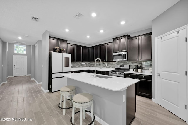 202 Purus Way, Jacksonville, FL 32259 - kitchen featuring stainless steel appliances, a sink, light wood-style floors, a kitchen breakfast bar, and tasteful backsplash