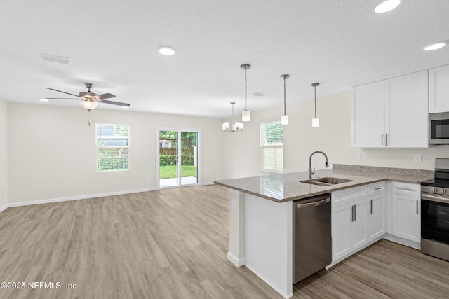 8204 Dandy Ave, Jacksonville, FL 32211 - kitchen with a sink, appliances with stainless steel finishes, light wood-style floors, white cabinets, and light stone countertops