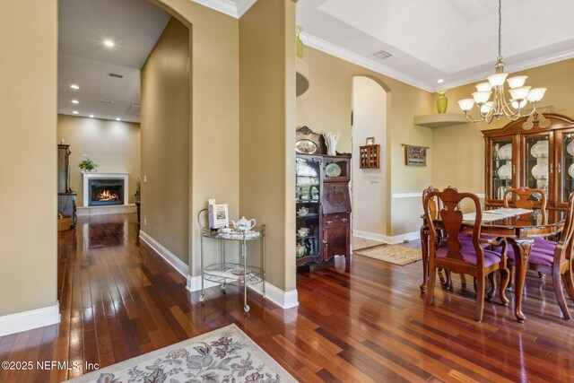 166 Mount Royal Ave, Crescent City, FL 32112 - dining room featuring arched walkways, hardwood / wood-style floors, a chandelier, a lit fireplace, and crown molding