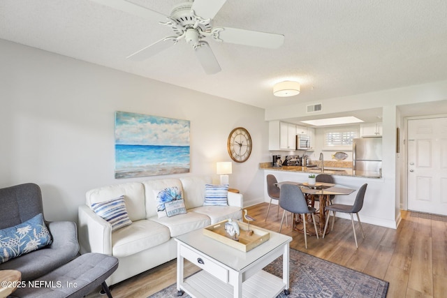 4250 A1A S Unit C15, Saint Augustine, FL 32080 - living area featuring light wood-style flooring, a ceiling fan, baseboards, and a textured ceiling