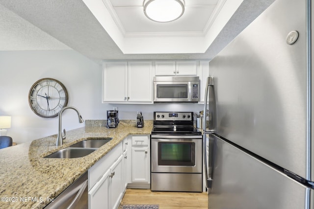 4250 A1A S Unit C15, Saint Augustine, FL 32080 - kitchen featuring stainless steel appliances, a sink, a tray ceiling, white cabinetry, and ornamental molding