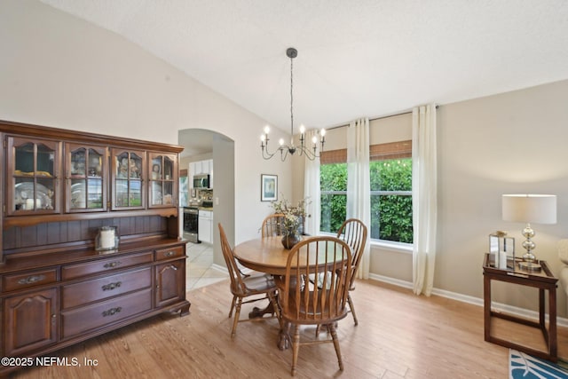 1494 Cedar Grove Ter, Fleming Island, FL 32003 - dining room with a chandelier, lofted ceiling, arched walkways, baseboards, and light wood-style flooring