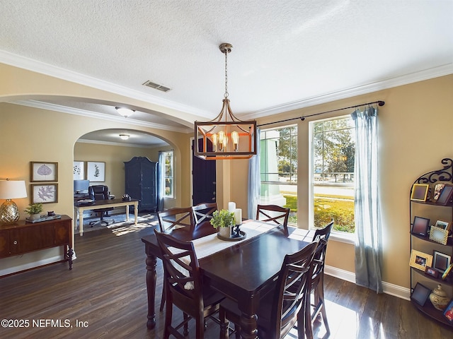 85667 Berryessa Way, Fernandina Beach, FL 32034 - dining space featuring arched walkways, a chandelier, dark wood-style floors, crown molding, and baseboards