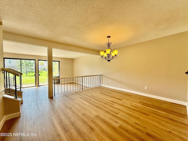 7779 Las Palmas Way Unit 114, Jacksonville, FL 32256 - unfurnished room featuring wood finished floors, baseboards, a textured ceiling, and a chandelier